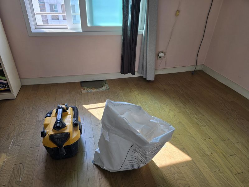 바닥 매립배관 보수 공사 중 절개 부위 주변 분진을 정리하는 모습